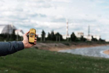 Pripyat, Ukrayna - 15 Ağustos 2019: Çernobil nükleer santrali yakınında radyometre tutan adamın kırpılmış görünümü 