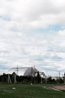 Pripyat, Ukrayna - 15 Ağustos 2019: bulutlarla gökyüzüne karşı yeşil ağaçların yanında terk edilmiş çernobil reaktörü 