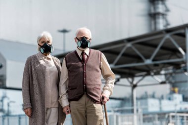 Pripyat, Ukrayna - 15 Ağustos 2019: terk edilmiş çernobil reaktörün yakınında duran koruyucu maskeli yaşlı kadın ve erkek 