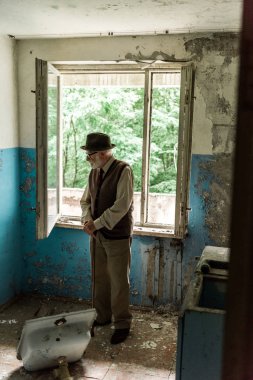 hasarlı odada baston yürüyüş ile ayakta üzgün yaşlı adam 
