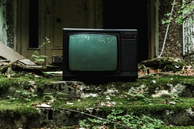 retro tv on green stairs with mold near building 