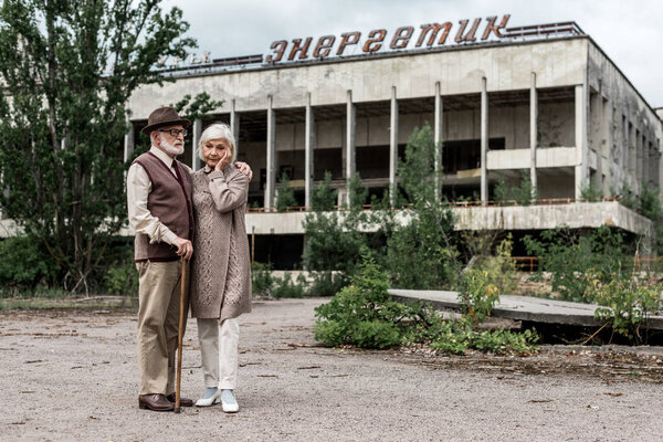 PRIPYAT, UKRAINE - AUGUST 15, 2019: retired couple standing near building with energetic lettering in chernobyl 