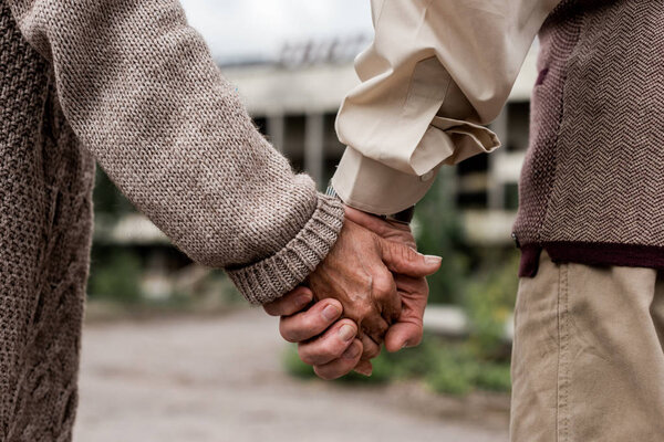 cropped view of retired man and woman holding hands 