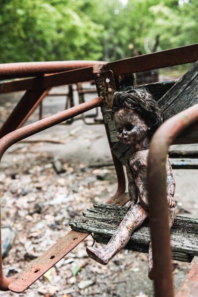 selective focus of burnt baby doll on abandoned carousel in chernobyl 