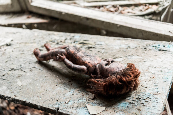 селективный фокус грязной и обожженной куклы на деревянном поврежденном столе
 