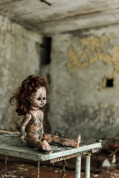 abandoned and burnt baby doll on dirty desk 