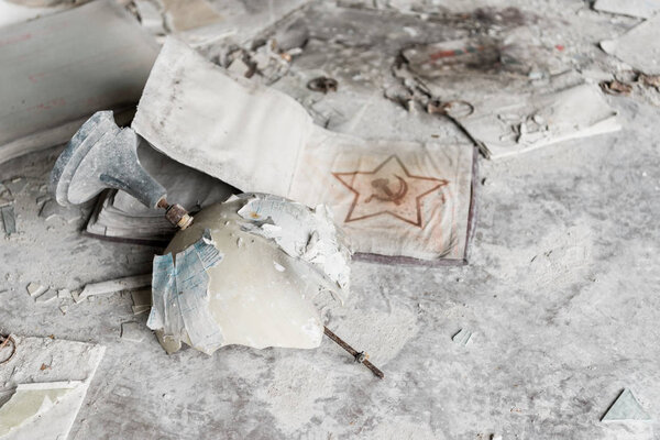 ПРИПЯТ, УКРАИНА - 15 августа 2019 года: разбитый земной шар возле советского профсоюзного знака на грязном полу
 