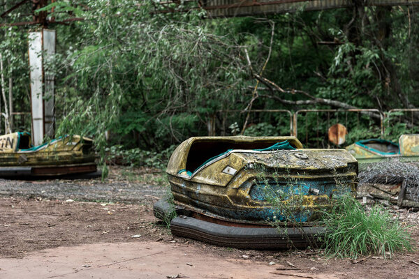 PRIPYAT, UKRAINE - AUGUST 15, 2019: selective focus of abandoned and dirty bumper cars in amusement park 