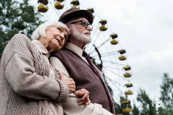 プリピャット ウクライナ 2019年8月15日 遊園地の観覧車の近くで夫を抱きしめる先輩女性の低角視野 — ストック写真