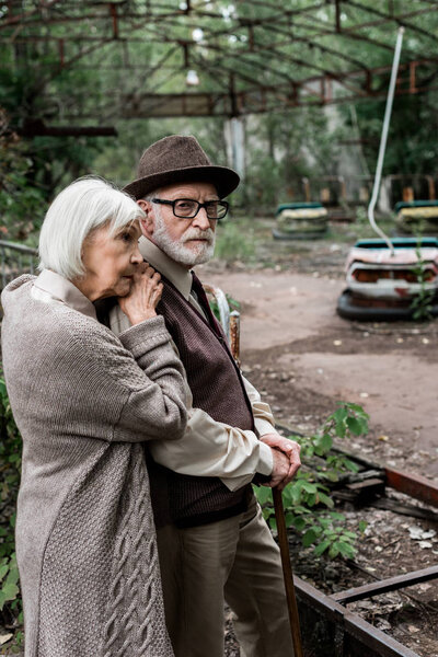 PRIPYAT, UKRAINE - AUGUST 15, 2019: sad senior woman standing with retired husband in hat 