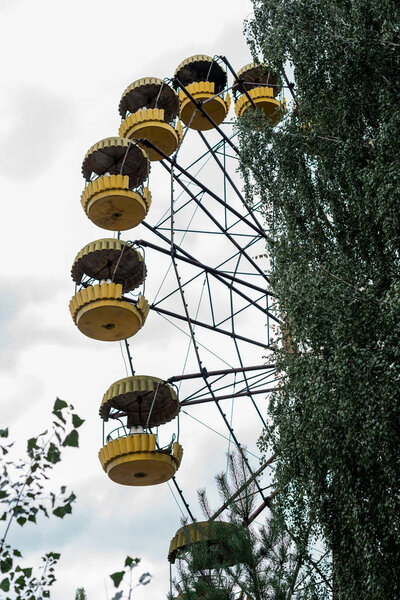 PRIPYAT, UKRAINE - AUGUST 15, 2019: rusty yellow ferris wheel in amusement park in chernobyl 