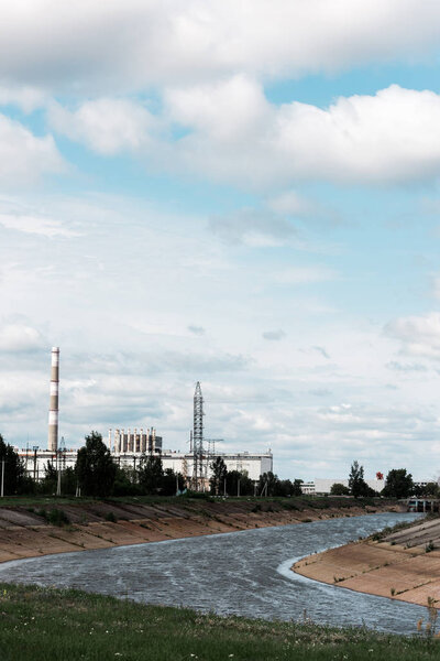 PRIPYAT, UKRAINE - AUGUST 15, 2019: abandoned chernobyl nuclear power plant near trees and river 