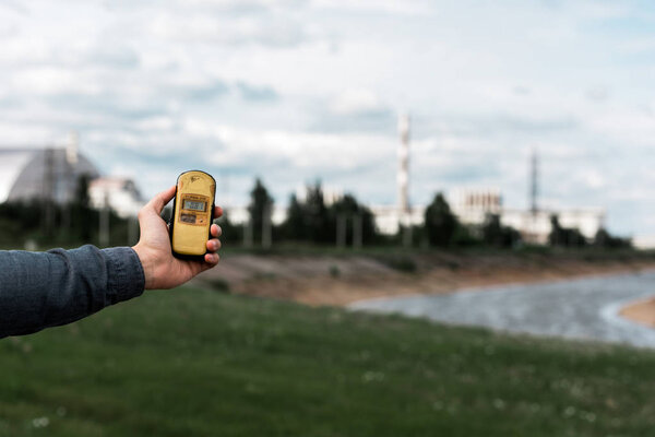 PRIPYAT, UKRAINE - AUGUST 15, 2019: cropped view of man holding radiometer near chernobyl nuclear power plant 