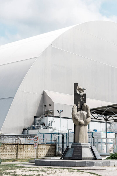 PRIPYAT, UKRAINE - AUGUST 15, 2019: concrete monument near abandoned chernobyl reactor against blue sky with clouds 