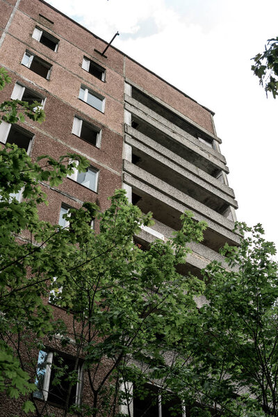 низкий угол обзора коричневого здания возле зеленых деревьев в Чернобыле
 