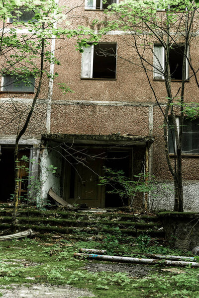 abandoned brown building with mold on stairs near green trees in chernobyl 