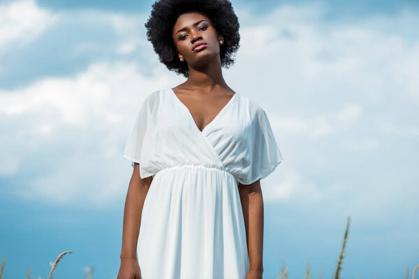 attractive african american woman in white dress against blue sky 