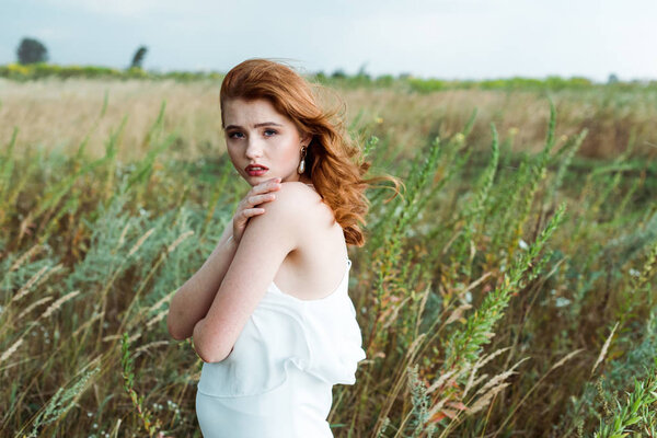 beautiful redhead woman in white dress looking at camera 