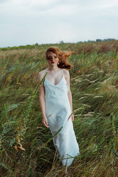 pretty young woman with red hair standing in dress 