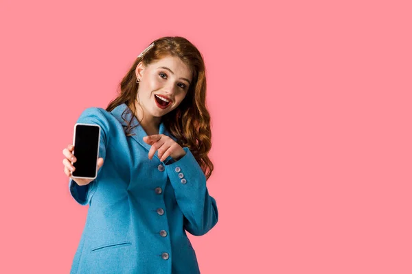 Excited Redhead Girl Holding Smartphone Blank Screen Pointing Finger Isolated — Stock Photo, Image