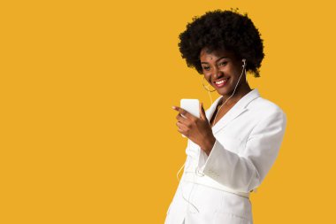 turuncu izole akıllı telefon tutarken müzik dinle mutlu afrikalı amerikalı kız 