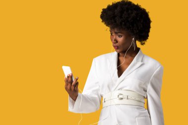 akıllı telefon tutan ve turuncu izole müzik dinleme afrikalı Amerikalı kadın şaşırttı