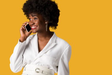 turuncu izole akıllı telefon konuşurken neşeli ve kıvırcık Afrikalı-Amerikalı kadın 
