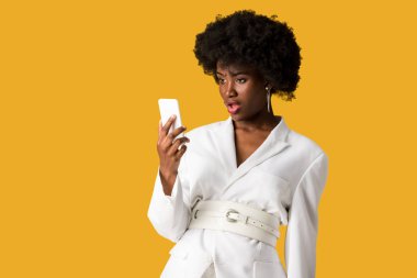 turuncu izole akıllı telefon bakarak şok kıvırcık Afrikalı-Amerikalı kadın 