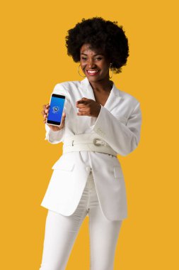 Kiev, Ukrayna - 9 Ağustos 2019: turuncu izole parmak ile işaret ederken ekranda shazam uygulaması ile akıllı telefon tutan mutlu Afrikalı Amerikalı kız 