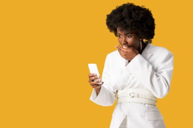 turuncu izole akıllı telefon bakarak şok kıvırcık Afrikalı-Amerikalı kadın 