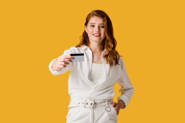 kredi kartı tutan mutlu genç kadın ve turuncu izole cebinde el ile ayakta 
