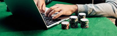 poker yongaları yakınında dizüstü bilgisayarda yazarak adam panoramik çekim