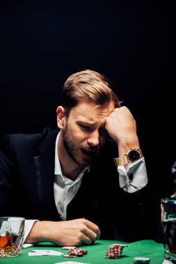 Masanın yanındaki üzgün adamın seçici odak noktası. Poker fişleri siyah üzerine izole edilmiş. 