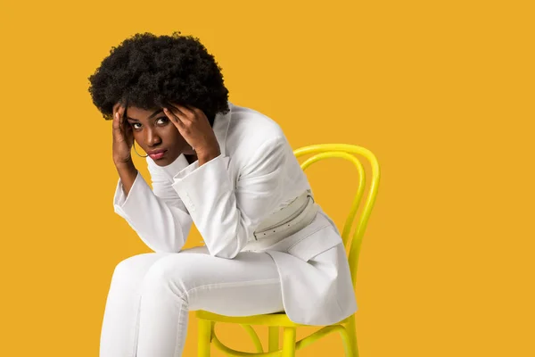 オレンジ色に隔離された黄色い椅子に座って疲れたアフリカ系アメリカ人の女の子 — ストック写真