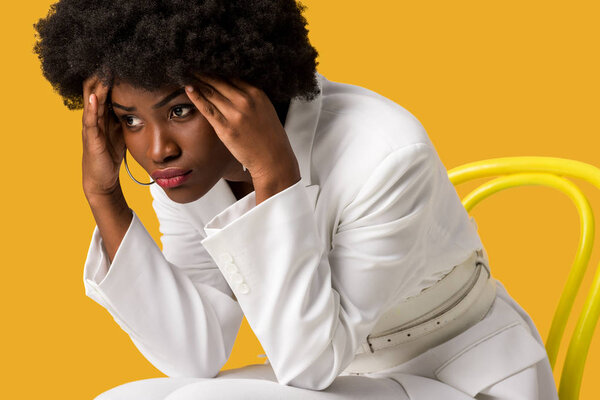 exhausted african american woman sitting on yellow chair isolated on orange 