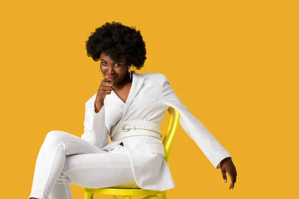 Smiling African American Woman Sitting Yellow Chair Pointing Finger Isolated — Stock Photo, Image