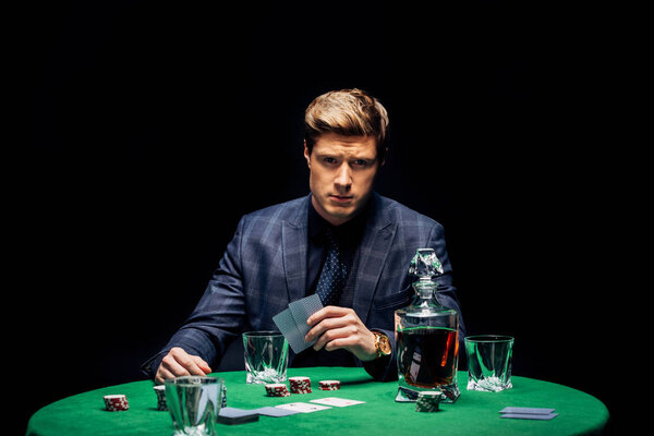 KYIV, UKRAINE - AUGUST 20, 2019: selective focus of man holding playing cards isolated on black 