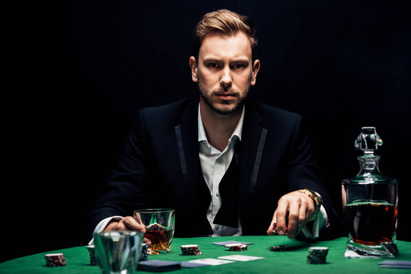 селективный фокус человека, держащего чипсы и стекло с алкоголем, изолированным на черном
 