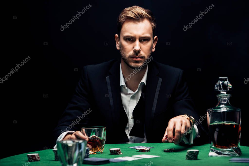 Selective focus of man holding poking chips and glass with alcohol isolated on black