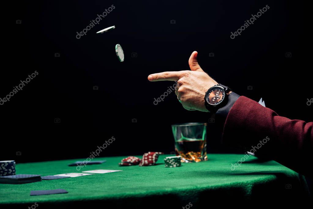 Cropped view man throwing in air poker chips isolated on black