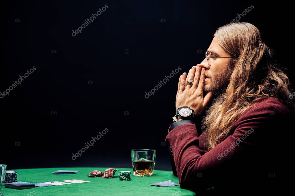 KYIV, UKRAINE - AUGUST 20, 2019: side view of man in eye glasses with praying hands isolated on black