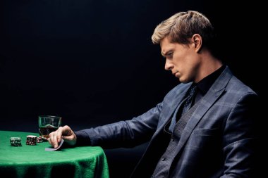 Kyiv, Ukrayna - 20 Ağustos 2019: Siyah üzerine poker oynarken kağıt oynayan yakışıklı adam 