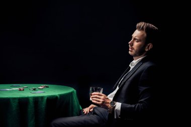 siyah izole poker masası yakınında cam tutan üzgün sakallı adam 