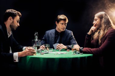 Kyiv, Ukrayna - 20 Ağustos 2019: Siyahla dumanla poker oynayan üç arkadaş 