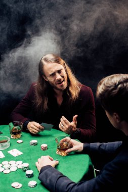 Kyiv, Ukrayna - 20 Ağustos 2019: Poker kulübünde elinde dumanla kağıt tutan adamın seçici odak noktası