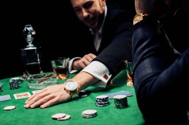 Kyiv, Ukrayna - 20 Ağustos 2019: siyah üzerine izole edilmiş poker çiplerine dokunan adamın seçici odak noktası