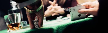 KYIV, UKRAINE - AUGUST 20, 2019: panoramic shot of man touching playing cards and poker chips near player clipart