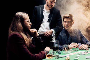 Kyiv, Ukrayna - 20 Ağustos 2019: Siyahla dumanla poker oynayan yakışıklı adamlar 
