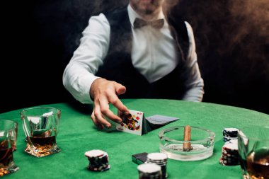 Kyiv, Ukrayna - 20 Ağustos 2019: Krupiyenin poker masasının yanında siyah dumanla kağıt oynaması görüntüsü 