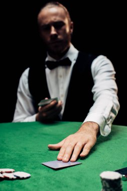 Kyiv, Ukrayna - 20 Ağustos 2019: Krupiyenin seçici odak noktası poker masasının üzerine izole edilmiş oyun kartı koymak 